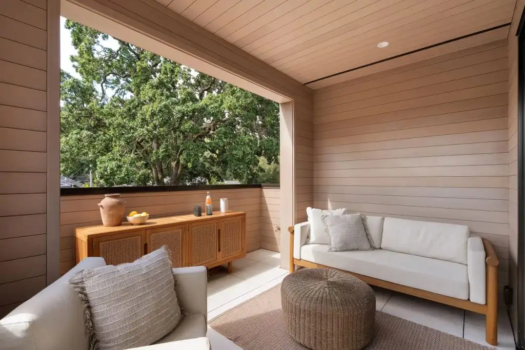 ACRE nickel gap siding used on covered outdoor porch walls and ceiling in neutral stain with seating area and tree views