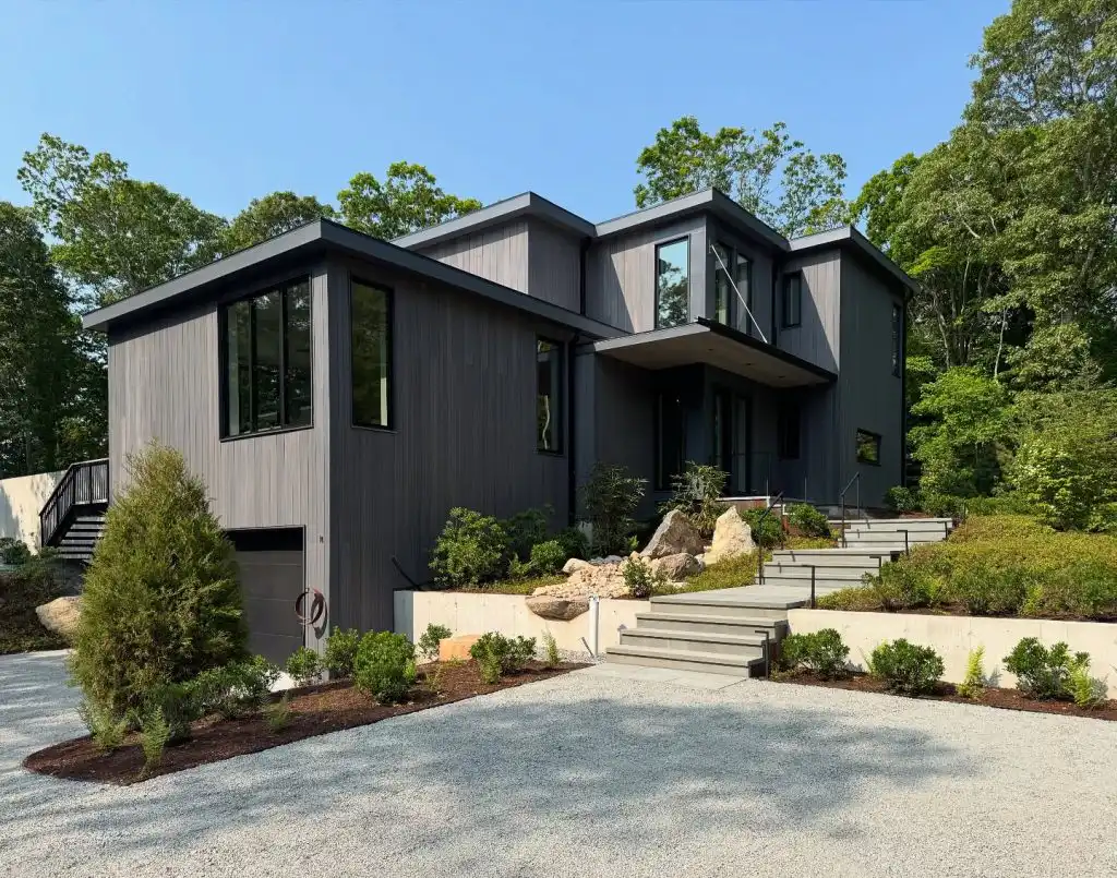 ACRE nickel gap siding installed vertically on modern home exterior in dark gray finish surrounded by trees