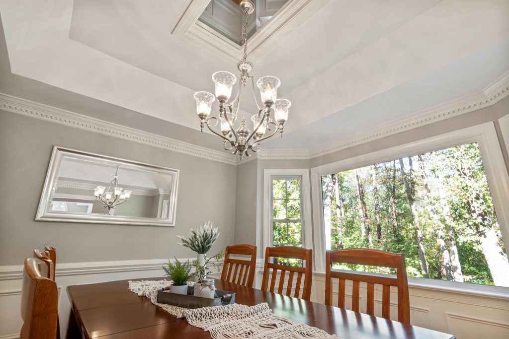 Dining room interior with white crown moulding at wall-to-ceiling junction and tray ceiling detail