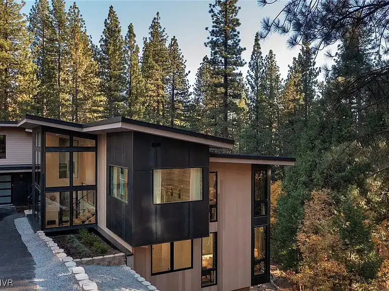 ACRE siding on a contemporary mountain home exterior featuring horizontal shiplap siding with dark vertical panel accents and floor-to-ceiling windows surrounded by pine trees