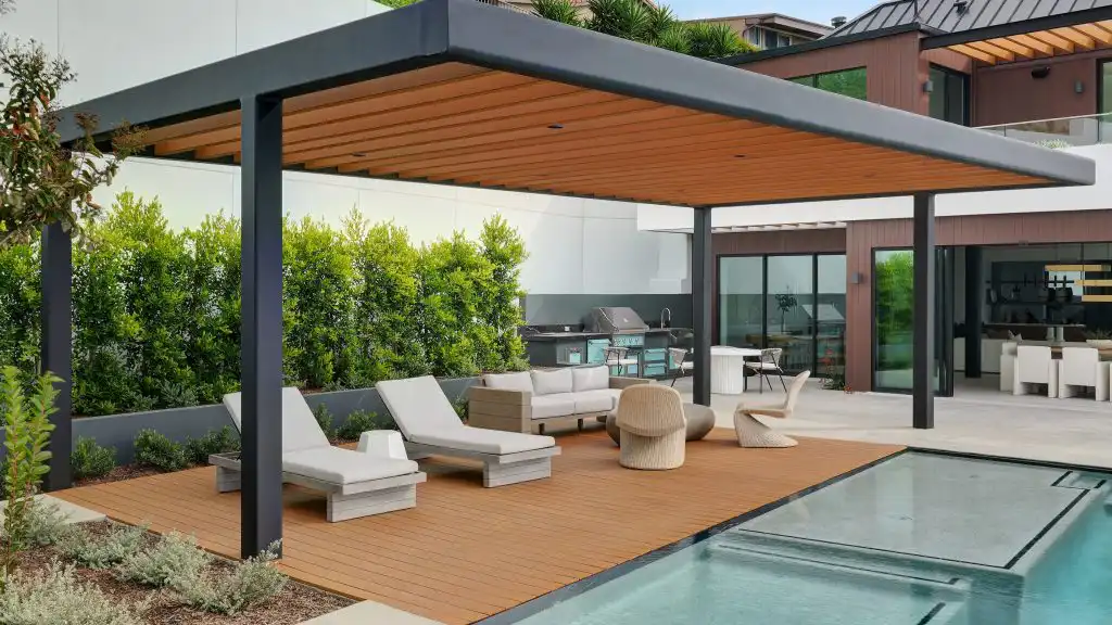 Modern outdoor living space with composite siding pergola, pool deck, lounge seating, and outdoor kitchen